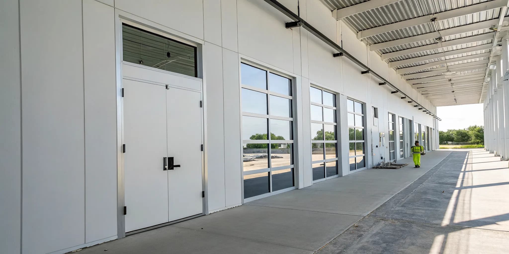 A person installing a commercial steel door into a prepared frame.